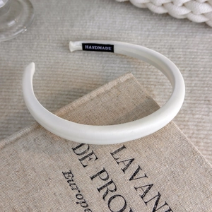 Detail of handmade cream padded sponge headband with satin texture on vintage book