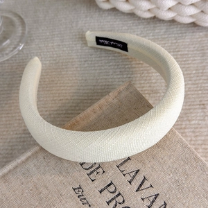 Detail of handmade cream padded headband with linen texture and black hand made label