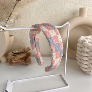 Detail of pink and blue checkered tweed headband on a stand in a warm cream setting