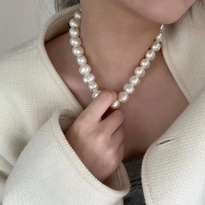 Elegant high-luster pearl choker necklace for women worn on a white tweed jacket outfit