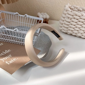 Détail de l'étiquette tissée à la main sur un serre-tête épais en satin couleur champagne