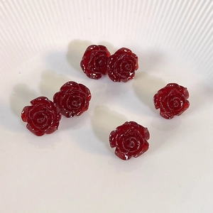 French vintage style red resin rose flower stud earrings displayed on a white ceramic plate