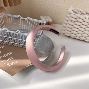 Détail du serre-tête rembourré en satin rose avec étiquette fait main et texture douce