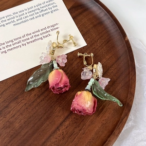 Detail van vintage roos clip-on oorbellen met roze bloemblaadjes en groene bladeren