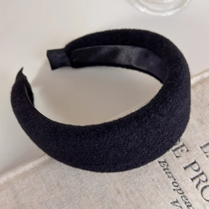 Detailed view of black thick padded headband with soft wool texture and satin lining