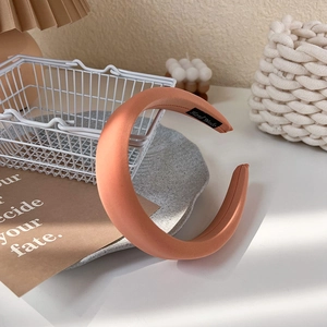 Gros plan d'un serre-tête en satin rose rembourré avec étiquette Hand Made sur un bureau