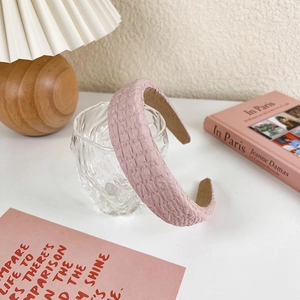 Close-up of pink bubble textured headband resting on a glass cup in a cozy setting
