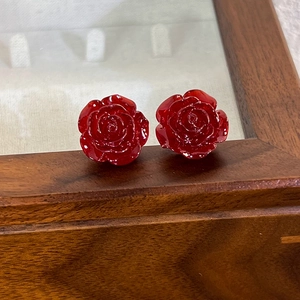 French vintage red pearlescent resin rose stud earrings on a wooden jewelry display box
