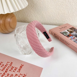 Detailed view of pink pleated wide headband with handmade label in a cozy setting