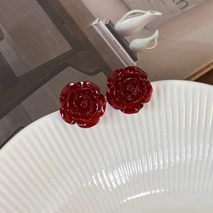 Detailed close-up of vintage resin red rose stud earrings on a ceramic plate