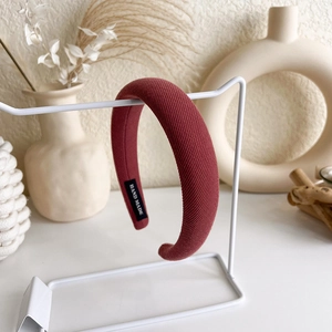 Detaillierte Makroansicht des dunkelroten Strick-Stirnbands mit schwarzem Hand Made Label