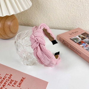 Detail of soft pink wide sponge headband with pleated fabric texture and knotted design