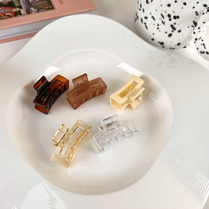 Close-up of five jelly colored rectangle hair claws arranged in a ceramic plate