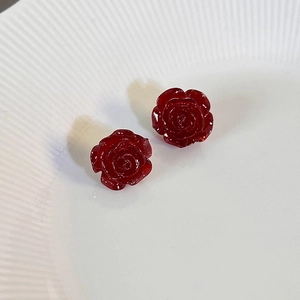 Detailed close-up of dark red resin rose stud earrings with layered vintage flower petals