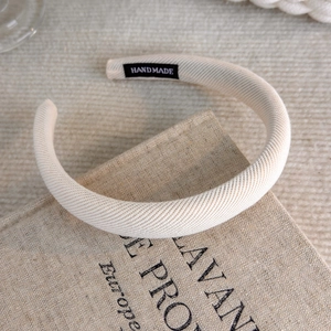 Detailed view of beige handmade fabric headband with woven texture and interior label