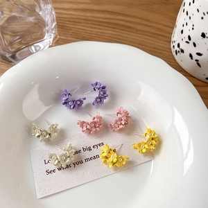 Detail of sweet floral earrings in purple, pink, beige, and yellow with pearl centers
