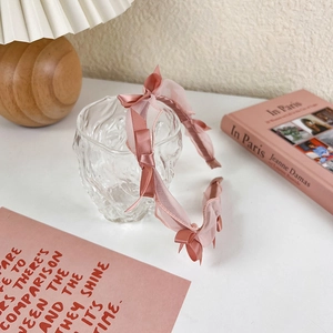 Detailed view of pink headband with satin bow and organza mesh on a glass bowl