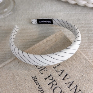 Detail of handmade cream fabric headband with black stripes on a vintage linen book