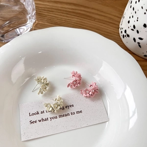 Detail of pink and beige 3D floral C-shaped stud earrings with delicate pearl accents