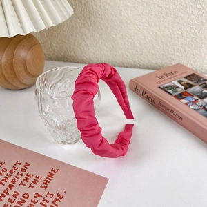 Detailed view of magenta pleated headband with silk texture on transparent glass base