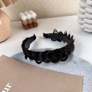 Detailed view of fishbone braided headband in dark brown on a minimalist stone tray