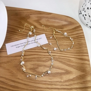 Elegant gold necklace and bracelet set featuring pearls and zircon on a wooden tray