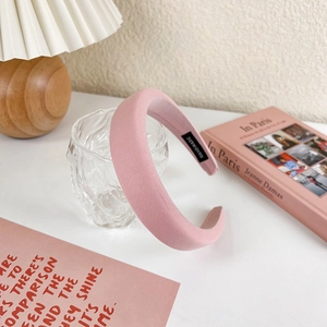 Detail of pink padded sponge headband with handmade label in a cozy home setting