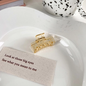 Detailed view of an amber transparent rectangular hair claw clip on a white heart plate