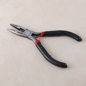 Détail d'une pince de bricolage pour bijoux avec manche noir antidérapant et tête en métal