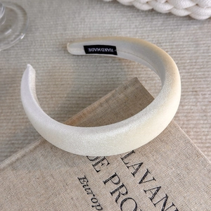 Detail of cream sponge headband with handmade label on vintage book background