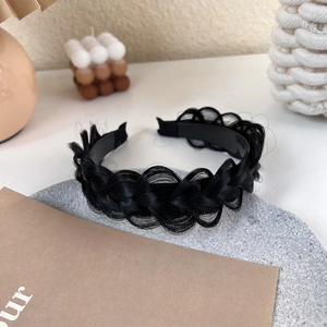 Detailed macro view of black fishtail braid headband with synthetic hair texture