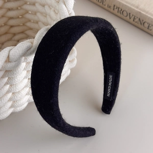 Detail of handmade black padded headband with woven wool texture and internal logo label