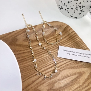 Flat lay of pearl and crystal necklace set on a wooden tray with aesthetic props