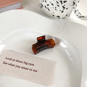 Detail shot of a small amber jelly hair claw clip on a stylish white ceramic plate