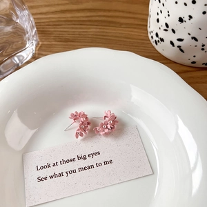 Detail of pink floral earrings with small white pearl centers on a decorative white plate