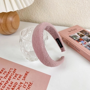 Detailed view of the pink ruffled fabric headband featuring a black handmade woven label
