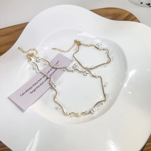 Detailed shot of golden wave necklace with pearls and crystals on a ceramic tray