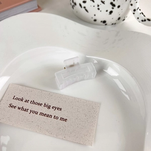 Detail of a 4cm white frosted rectangle hair claw clip on a stylish ceramic plate
