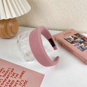 Detailed view of pink padded headband with waffle texture and handmade label on desk