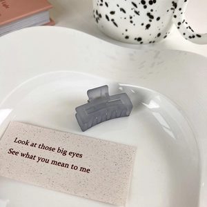 Close-up of a matte gray rectangular hollow hair claw clip on a white ceramic plate