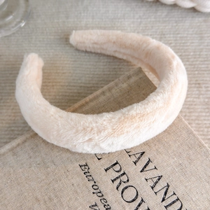 Detail of soft cream beige faux fur headband texture placed on a vintage book
