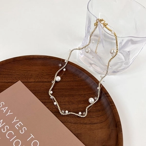 Detail of floating pearl necklace with rhinestones on transparent line with gold clasp