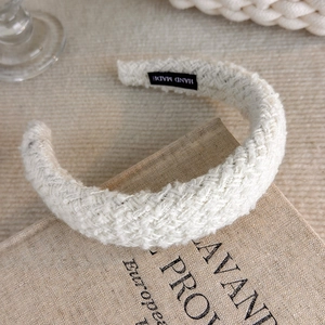 Close-up of beige tweed headband with Hand Made label on a vintage book
