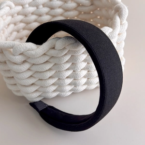 Detail of black knitted wide headband featuring non-slip lining and soft fabric texture