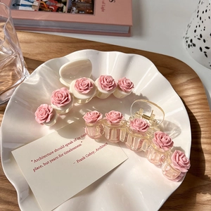 Pink camellia hair claws in cream and clear styles on a white shell tray for women