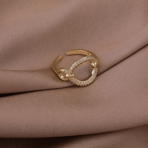 Macro shot of gold adjustable ring with round sparkling zircon circle on satin background