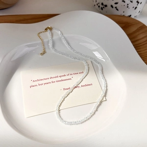 Dettaglio di una collana di perle di cristallo trasparente con chiusura dorata e piccolo ciondolo