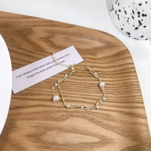 Detail of elegant gold necklace with pearls and rhinestones on a minimalist wooden tray