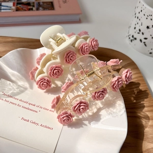 Pink camellia hair claw clips in ivory and transparent styles on a white tray