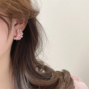 Pink floral C-shaped hoop earrings with pearl center petals worn by a model